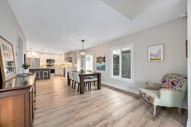 dining area featuring an inviting chandelier, light wood-style flooring, and baseboards