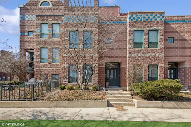 view of front of home featuring brick siding and fence