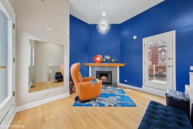 sitting room featuring a premium fireplace, baseboards, and wood finished floors