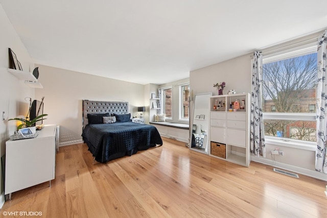 bedroom featuring visible vents, multiple windows, baseboards, and light wood finished floors