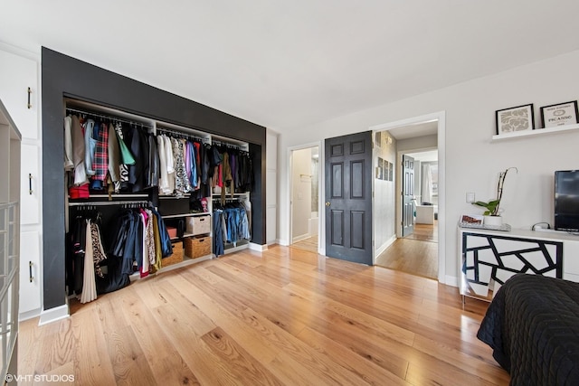 bedroom featuring light wood finished floors, baseboards, and a closet