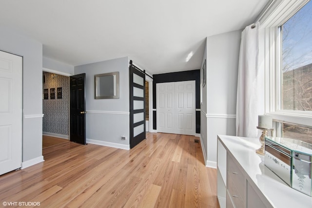 entryway featuring a wealth of natural light, baseboards, light wood-style floors, and a barn door