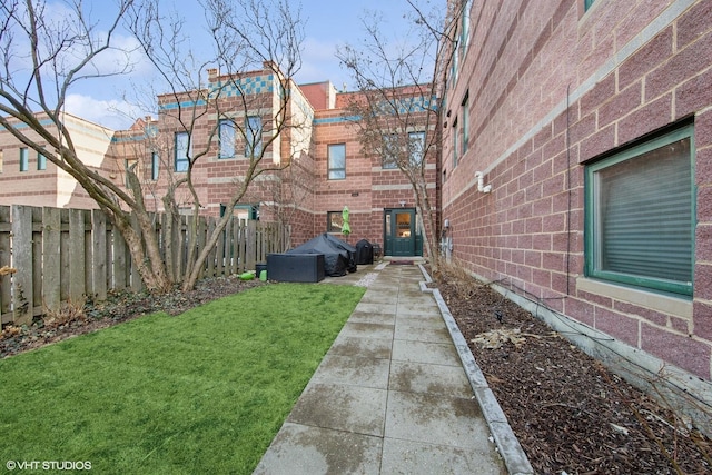 exterior space with brick siding, a yard, and fence