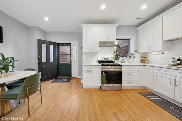 kitchen with stainless steel range with gas stovetop, light countertops, light wood-style floors, under cabinet range hood, and white cabinetry