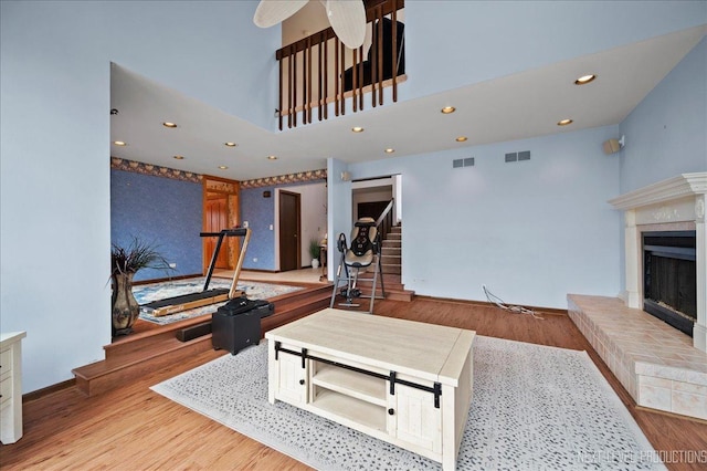 living room featuring visible vents, a brick fireplace, stairs, and wood finished floors