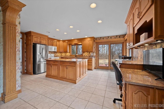 kitchen with white microwave, stainless steel fridge with ice dispenser, light tile patterned floors, light stone counters, and electric stove