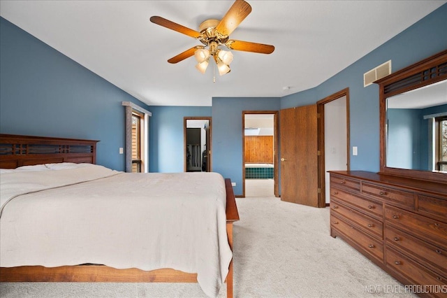 bedroom with ensuite bath, light colored carpet, visible vents, and ceiling fan