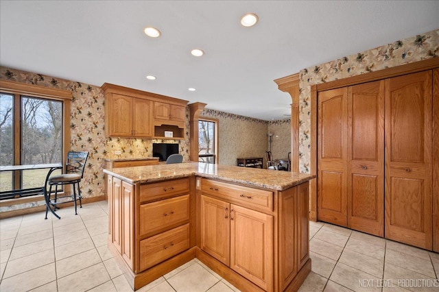 kitchen with light stone counters, a healthy amount of sunlight, and wallpapered walls