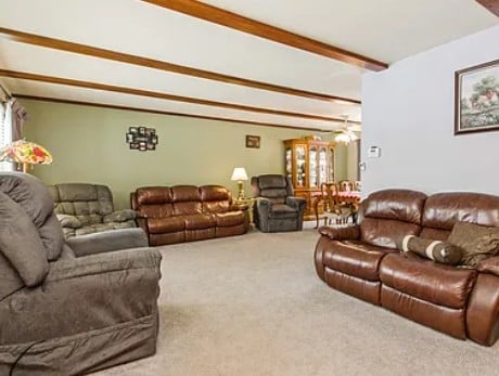 living area featuring beam ceiling and carpet