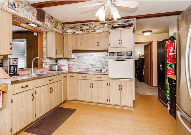 kitchen featuring light brown cabinetry, white oven, black electric cooktop, and a sink