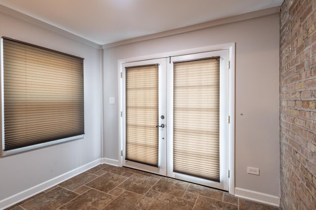 doorway with french doors, brick wall, stone finish floor, and baseboards