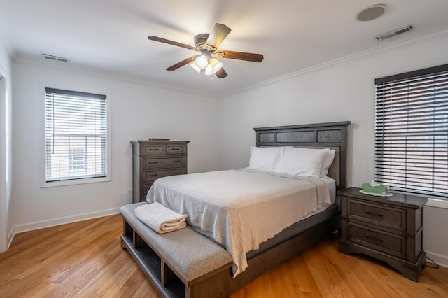 bedroom with baseboards, light wood-type flooring, visible vents, and crown molding