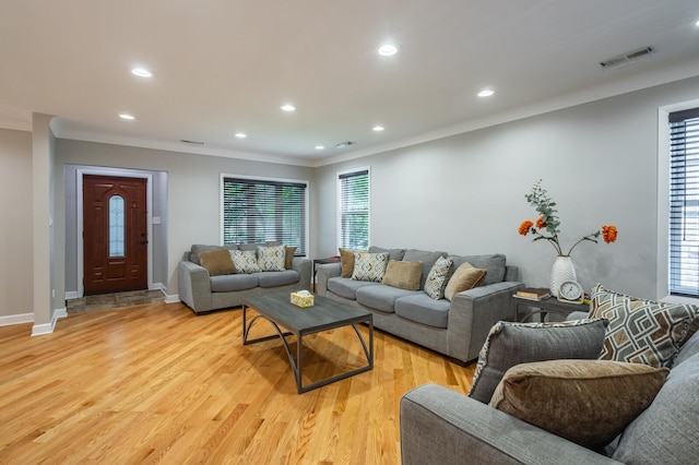 living room featuring light wood finished floors, baseboards, visible vents, ornamental molding, and recessed lighting