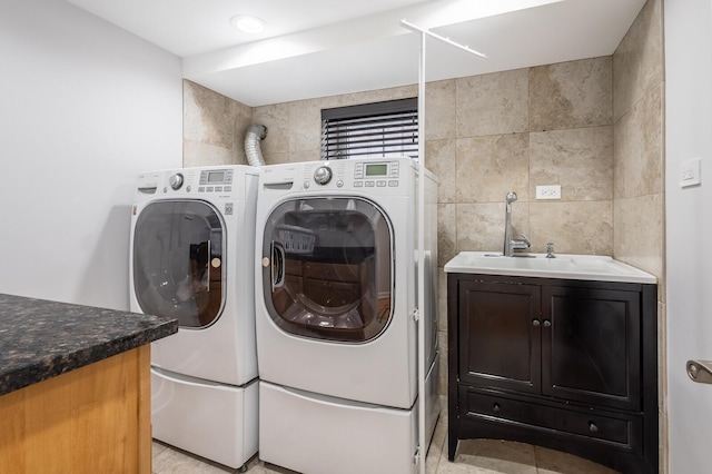 clothes washing area featuring cabinet space, independent washer and dryer, tile walls, and a sink