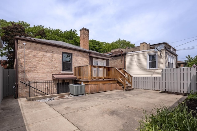 rear view of property featuring a deck, a patio, central AC unit, brick siding, and fence