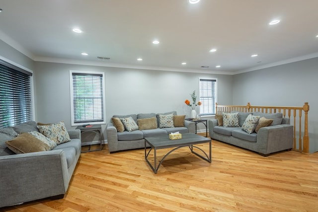 living room with light wood-type flooring, visible vents, crown molding, and recessed lighting