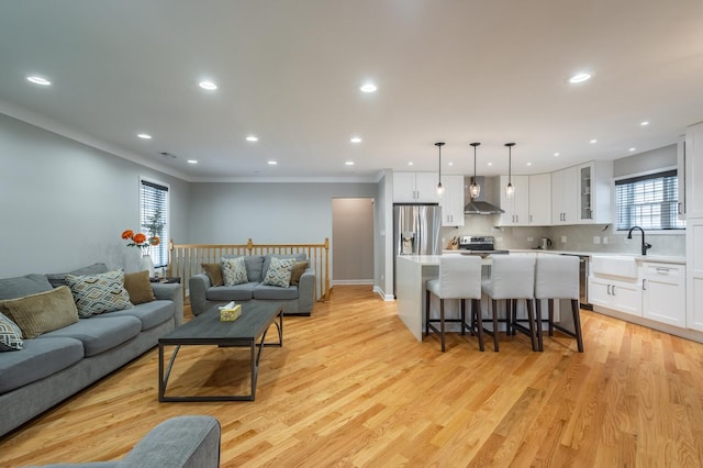 living room with ornamental molding, light wood finished floors, a wealth of natural light, and recessed lighting