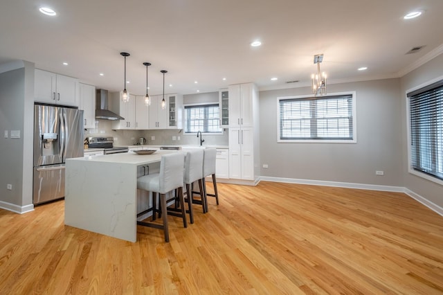 kitchen with tasteful backsplash, visible vents, a kitchen island, stainless steel appliances, and wall chimney range hood