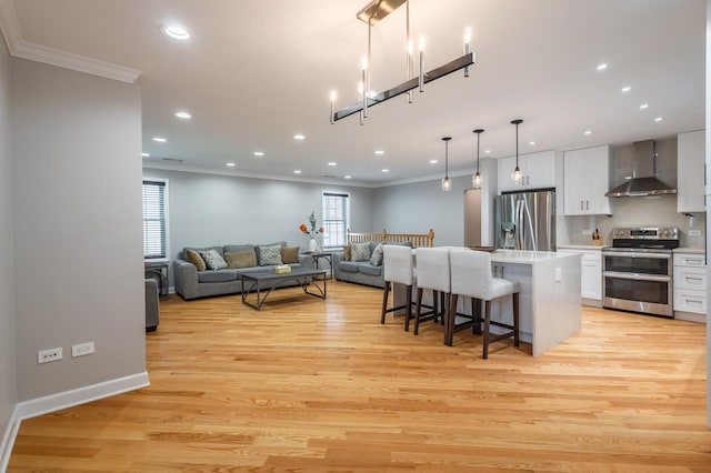 kitchen featuring wall chimney range hood, appliances with stainless steel finishes, a breakfast bar area, and ornamental molding