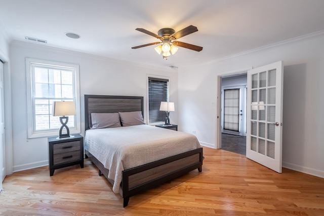 bedroom with ornamental molding, light wood-type flooring, visible vents, and baseboards