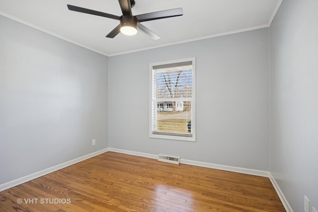 unfurnished room featuring ornamental molding, wood finished floors, visible vents, and baseboards