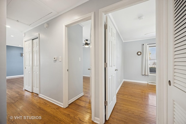 corridor featuring visible vents, attic access, baseboards, and wood finished floors