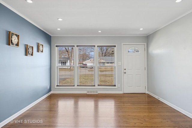 unfurnished dining area with visible vents, baseboards, wood finished floors, and crown molding