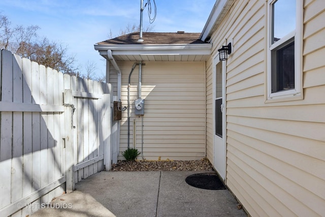 exterior space featuring a patio, a shingled roof, and fence