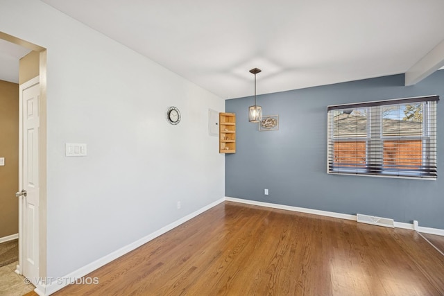 unfurnished room featuring visible vents, baseboards, and wood finished floors