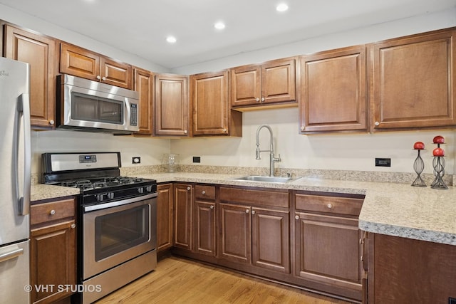 kitchen with light countertops, light wood-style floors, appliances with stainless steel finishes, and a sink