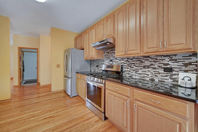 kitchen featuring under cabinet range hood, light brown cabinets, light wood-style floors, decorative backsplash, and appliances with stainless steel finishes