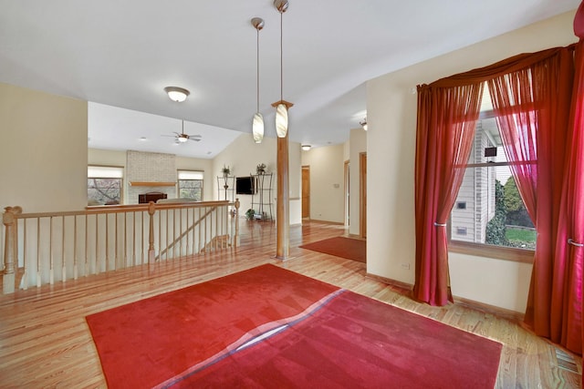 empty room with vaulted ceiling, wood finished floors, a ceiling fan, and baseboards
