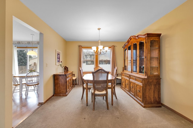 dining space with carpet flooring, baseboards, and a chandelier