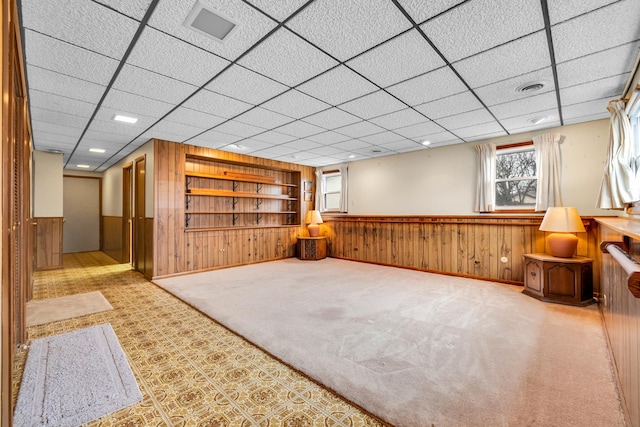 below grade area with visible vents, built in features, wood walls, carpet flooring, and wainscoting