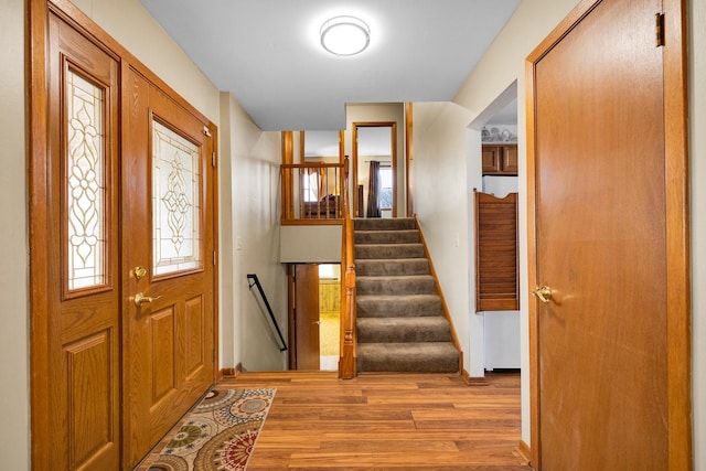 entryway with stairs, wood finished floors, and baseboards