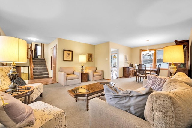 carpeted living area featuring stairway, a healthy amount of sunlight, and an inviting chandelier