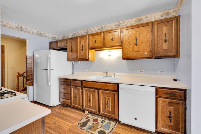 kitchen with white appliances, light countertops, brown cabinets, and a sink