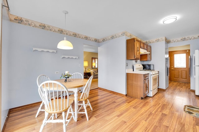 kitchen with under cabinet range hood, light countertops, light wood-style flooring, brown cabinets, and white appliances