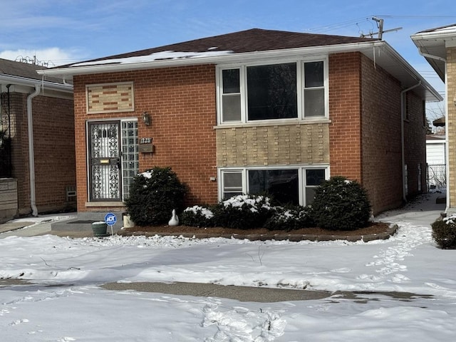 view of snowy exterior with brick siding