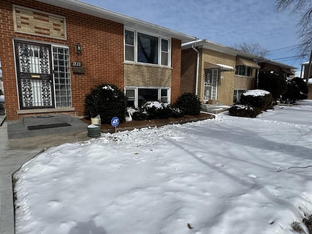 view of snowy exterior with brick siding