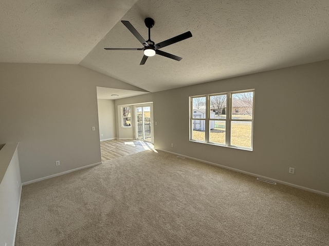 unfurnished room with light carpet, vaulted ceiling, and a textured ceiling