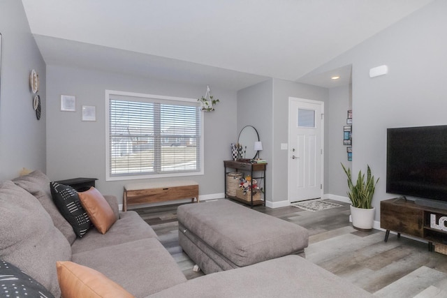 living area with vaulted ceiling, baseboards, and wood finished floors