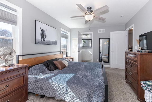 bedroom with ensuite bath, a ceiling fan, visible vents, and light carpet