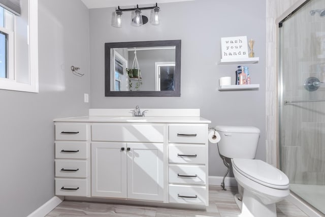 bathroom with baseboards, vanity, toilet, and a shower stall