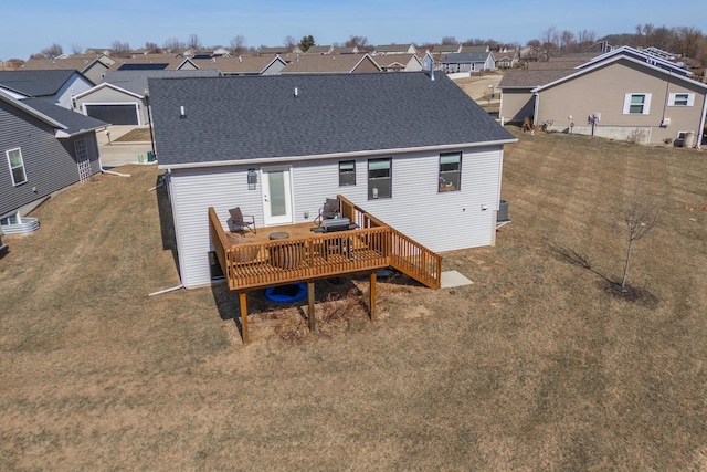 back of house featuring a wooden deck, a residential view, a yard, and roof with shingles