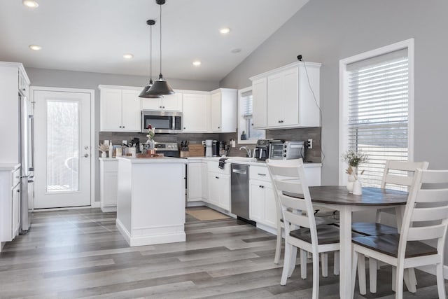 kitchen featuring white cabinetry, decorative backsplash, appliances with stainless steel finishes, and a kitchen island