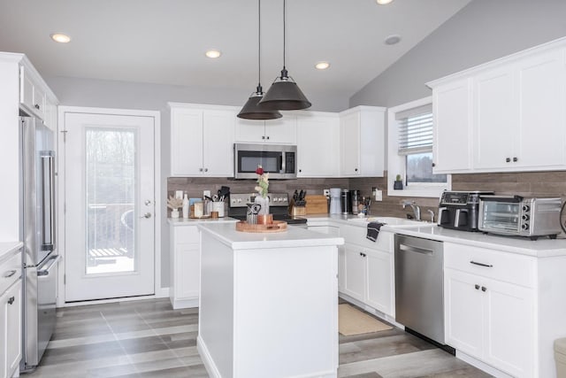 kitchen featuring a kitchen island, a toaster, appliances with stainless steel finishes, white cabinetry, and a sink