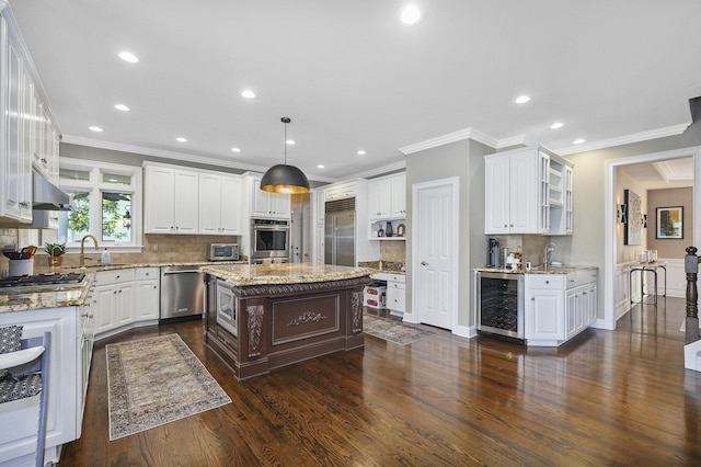 kitchen with beverage cooler, a sink, dark wood-type flooring, white cabinets, and built in appliances