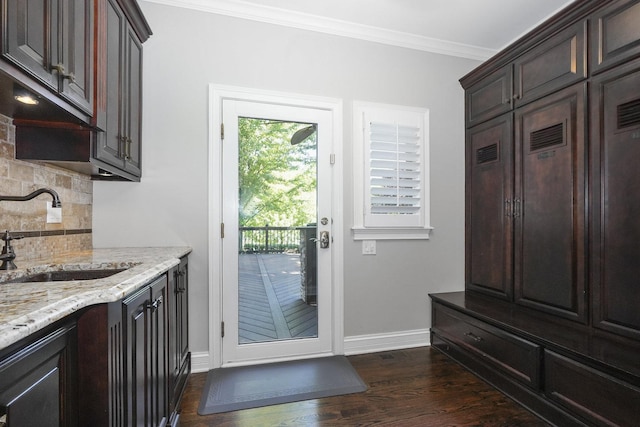 doorway with ornamental molding, baseboards, dark wood-style flooring, and a sink