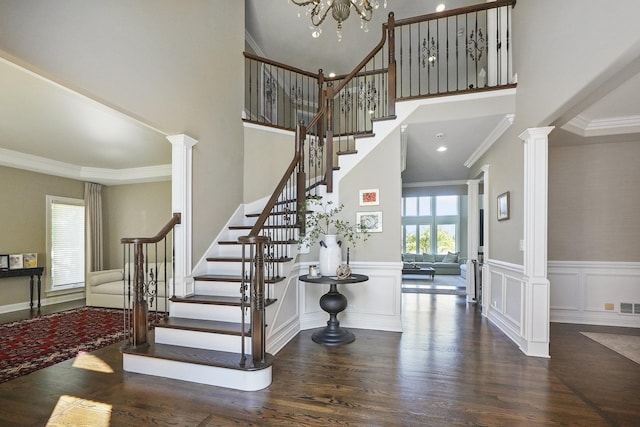 staircase featuring crown molding, decorative columns, and wood finished floors